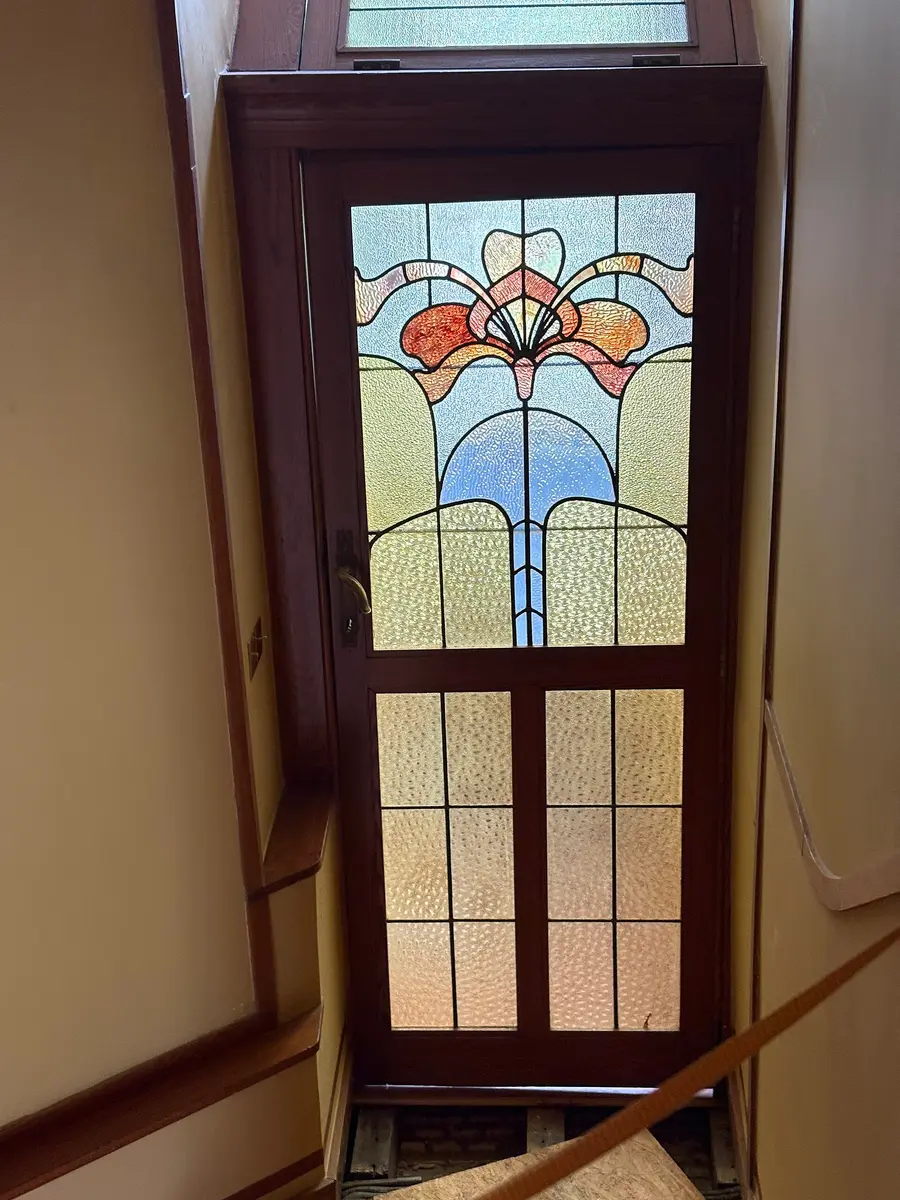A stained-glass door panel with a flower in red, gold and blue