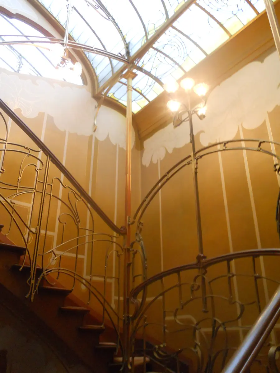 Iron banisters climbing towards the skylight in the stairwell of Horta's house