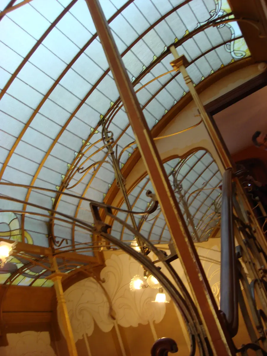 Looking up through the stairwell to the skylight, with brass lamps and curving iron rails