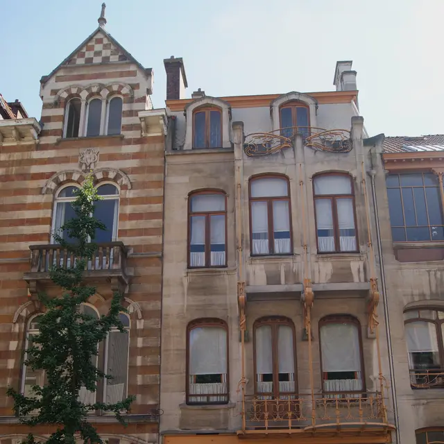 The narrow stone front of Horta's house on rue Américaine, with its iron balcony and carved wooden door